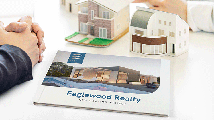 Sur un bureau d'agent immobilier on voit 2 petites maquettes de maison et devant est posé un document relier